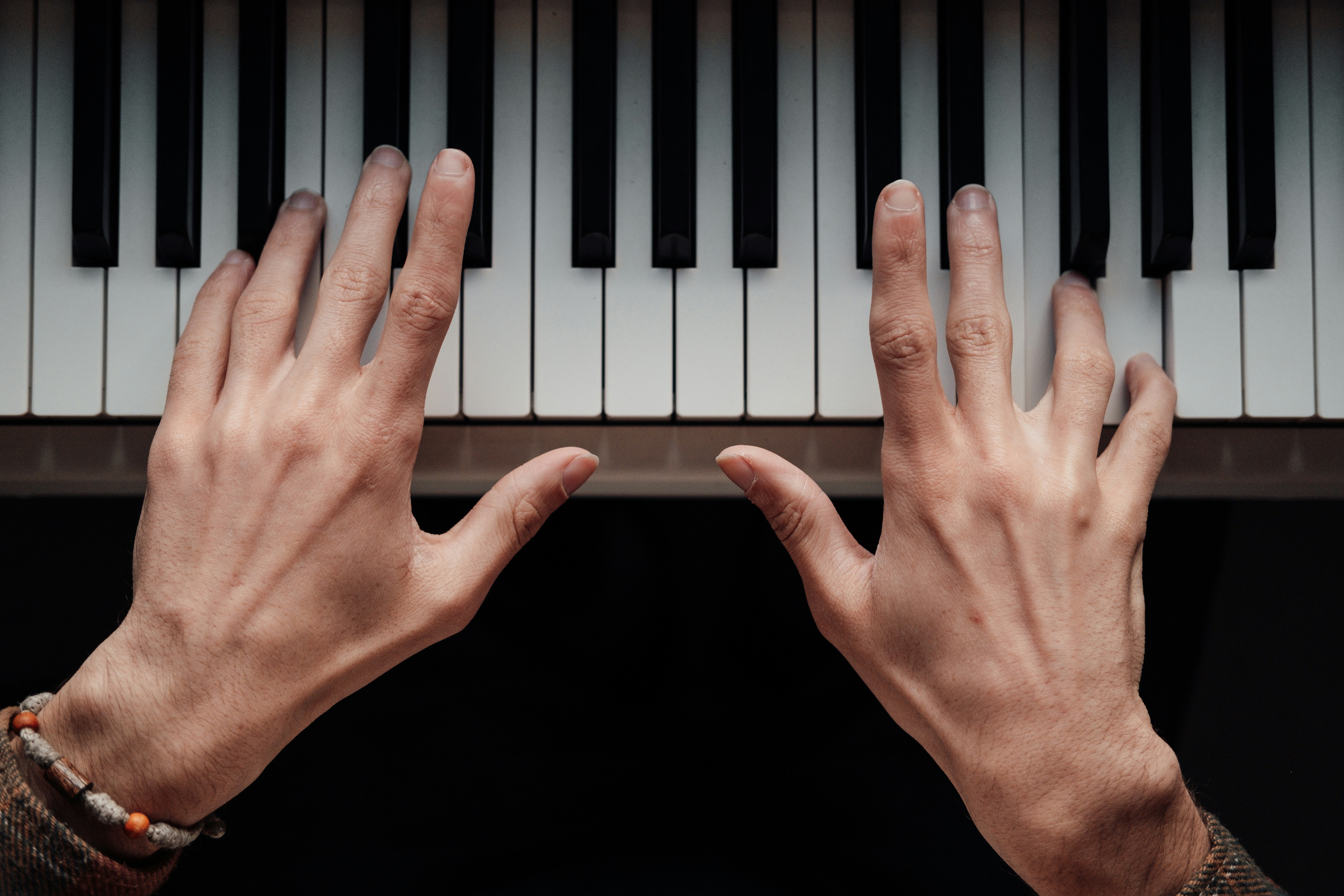 Hands reaching for a piano keyboard.