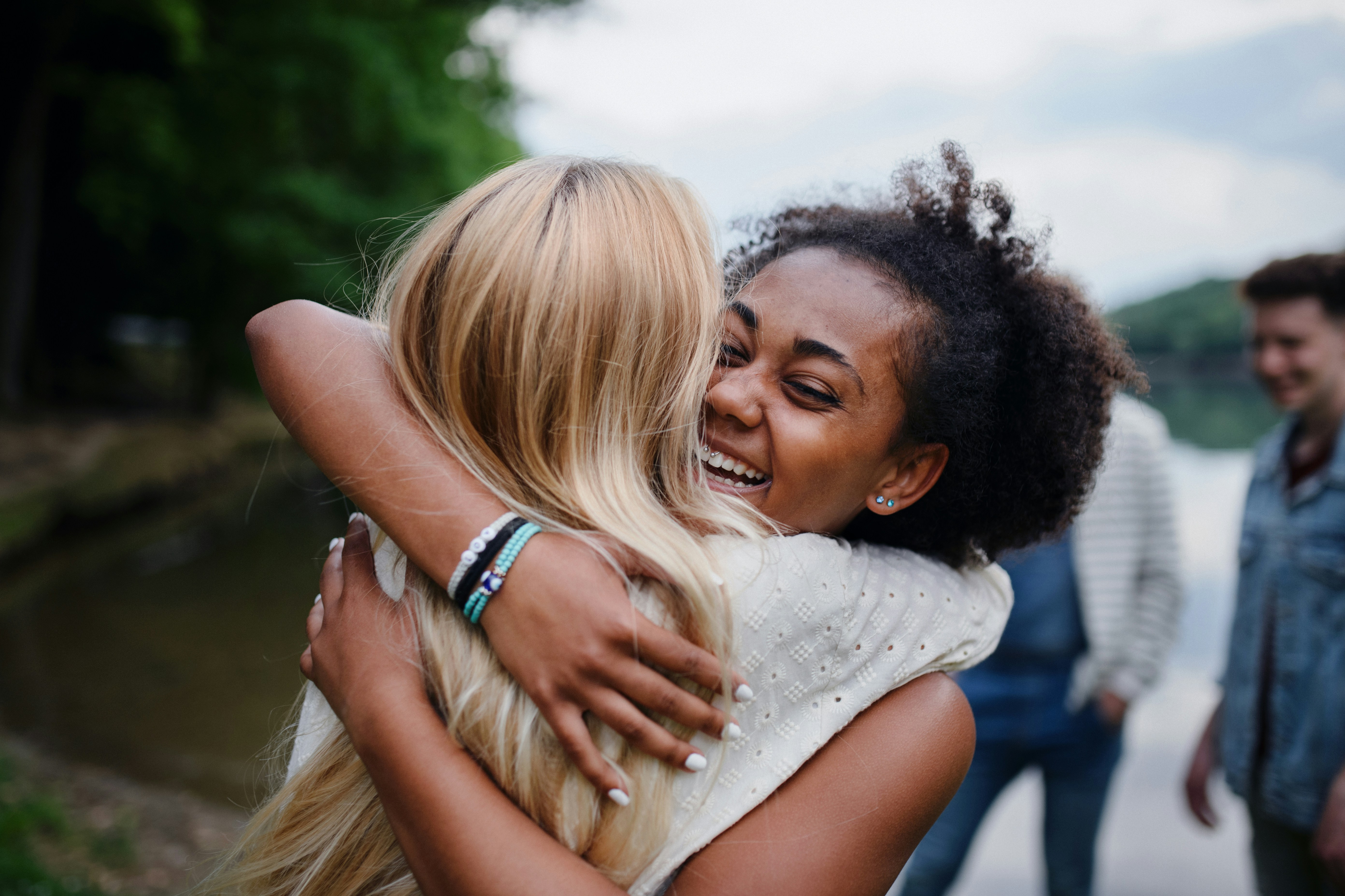 Friends having fun together in the park and hugging each other.