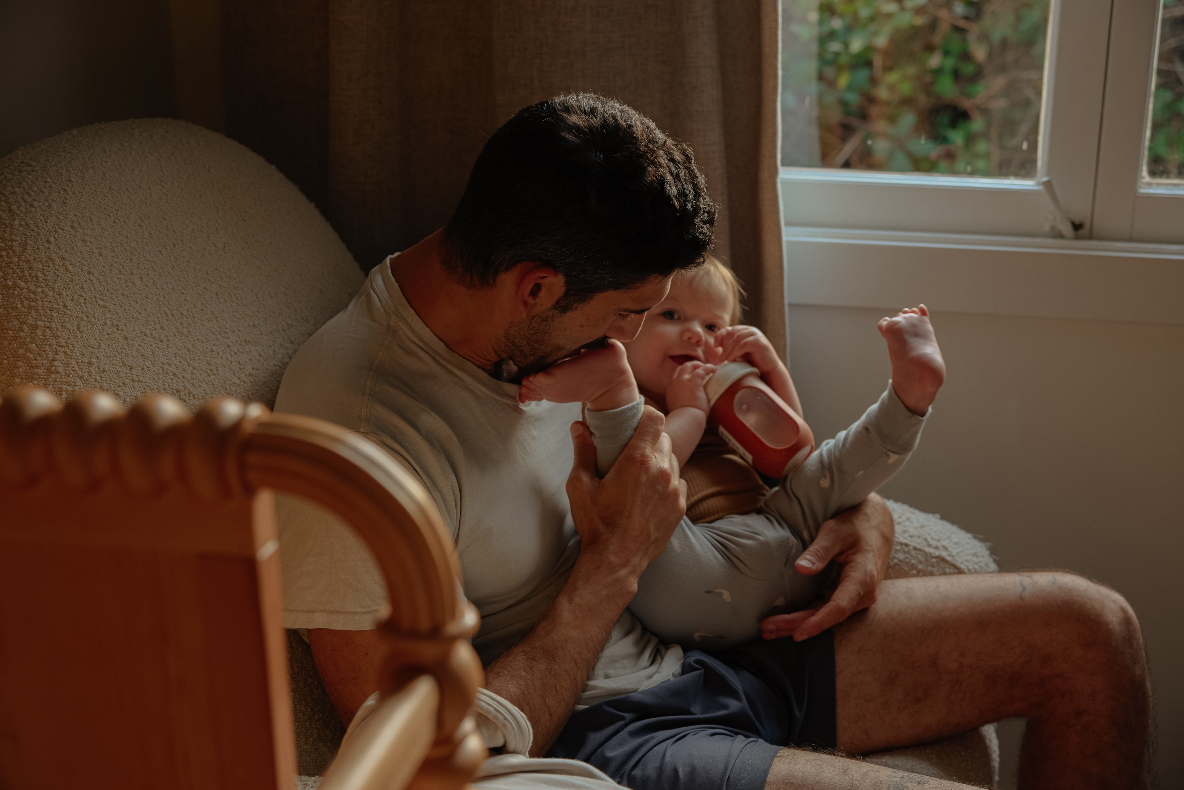 Father sitting and playing with the foot of his baby daughter.